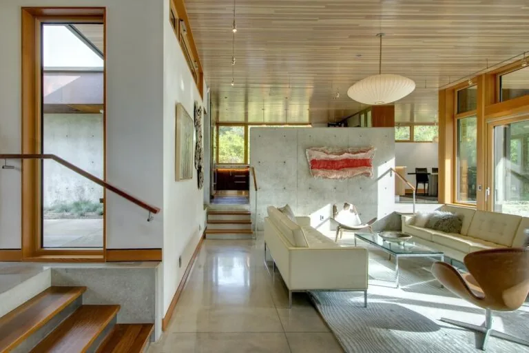 Living room of Montana Creekside Residence features concrete floor, wood ceiling, and modern furnishings by Studio Zerbey.