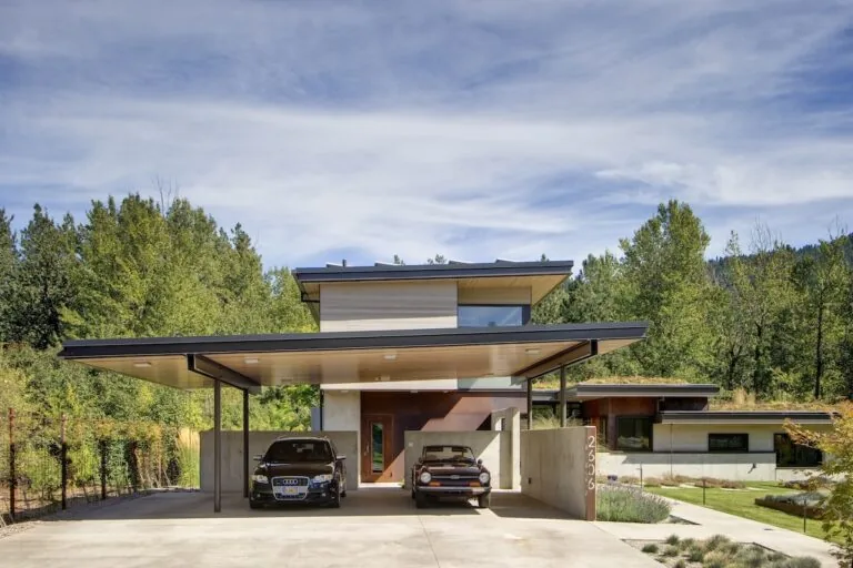 Montana Creekside Residence features a modern design with a flat roof carport and wood-paneled ceiling.