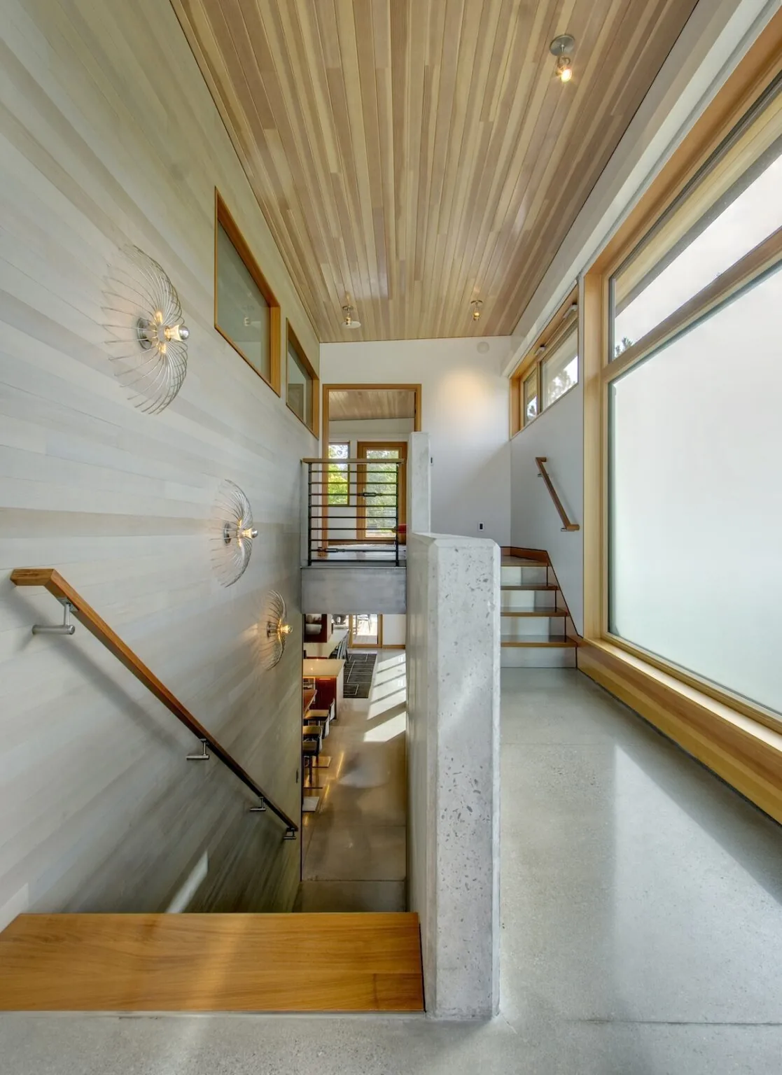 The Montana Creekside Residence features a stairwell with wood-paneled ceiling and large frosted window for natural light.