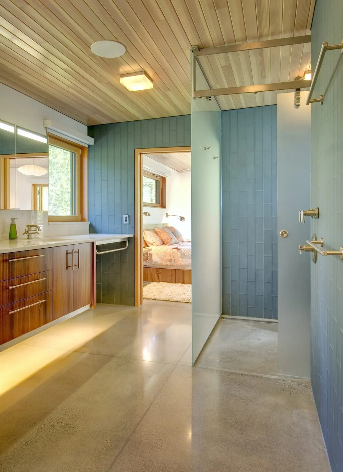Bathroom in Montana Creekside Residence features wood ceiling, blue tile walls, and a walk-in shower adjacent to a bedroom