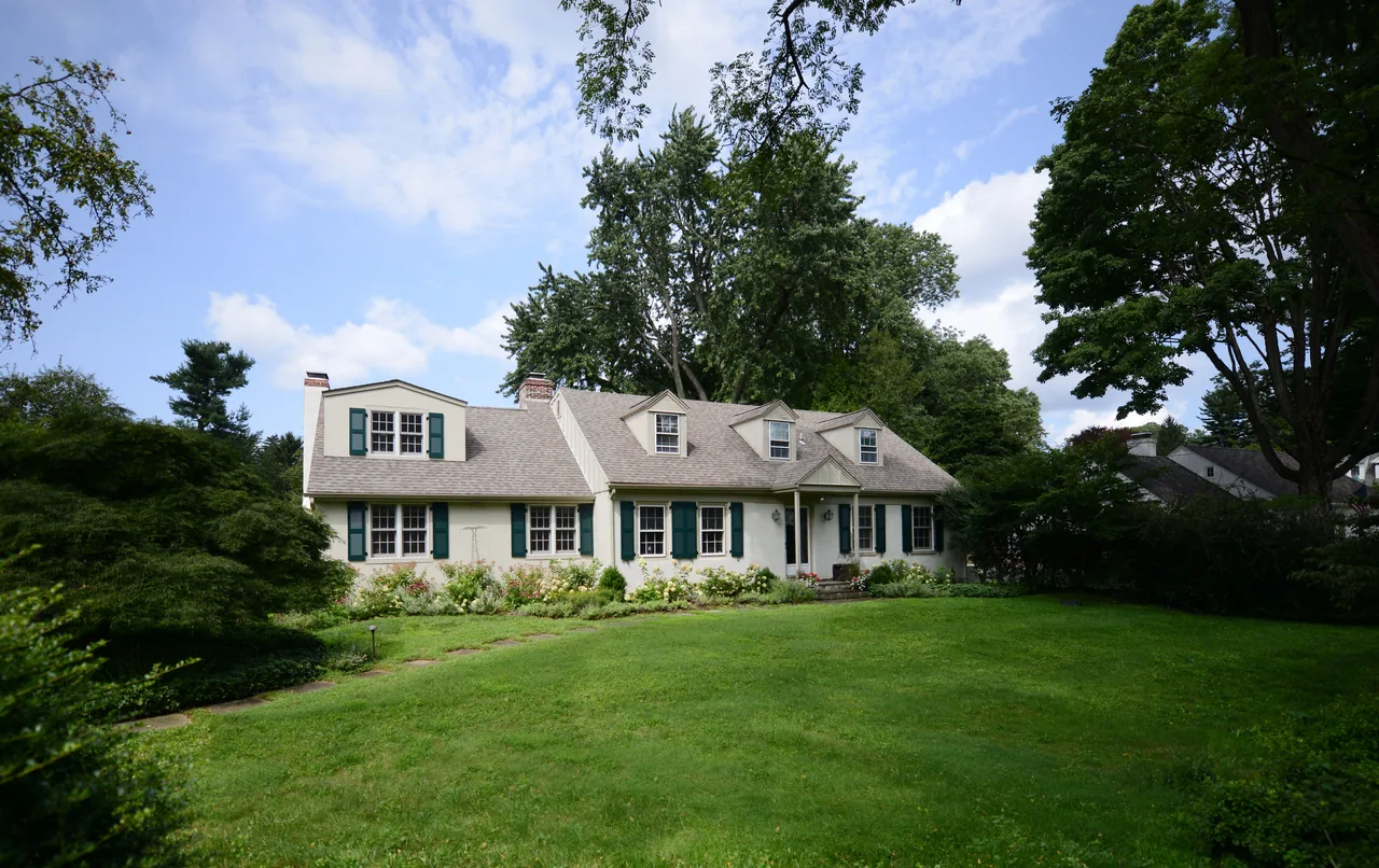 The Church residence features a traditional gable roof with dormers and green window shutters, set amidst a spacious, landscaped lawn.