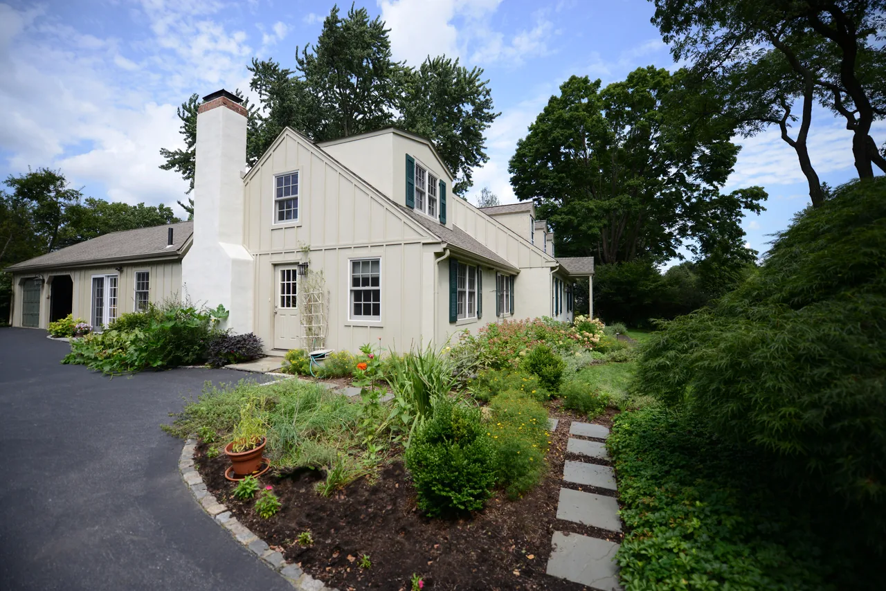 Traditional style residence featuring dormer windows, green shutters, and landscaped lawn in Philadelphia.