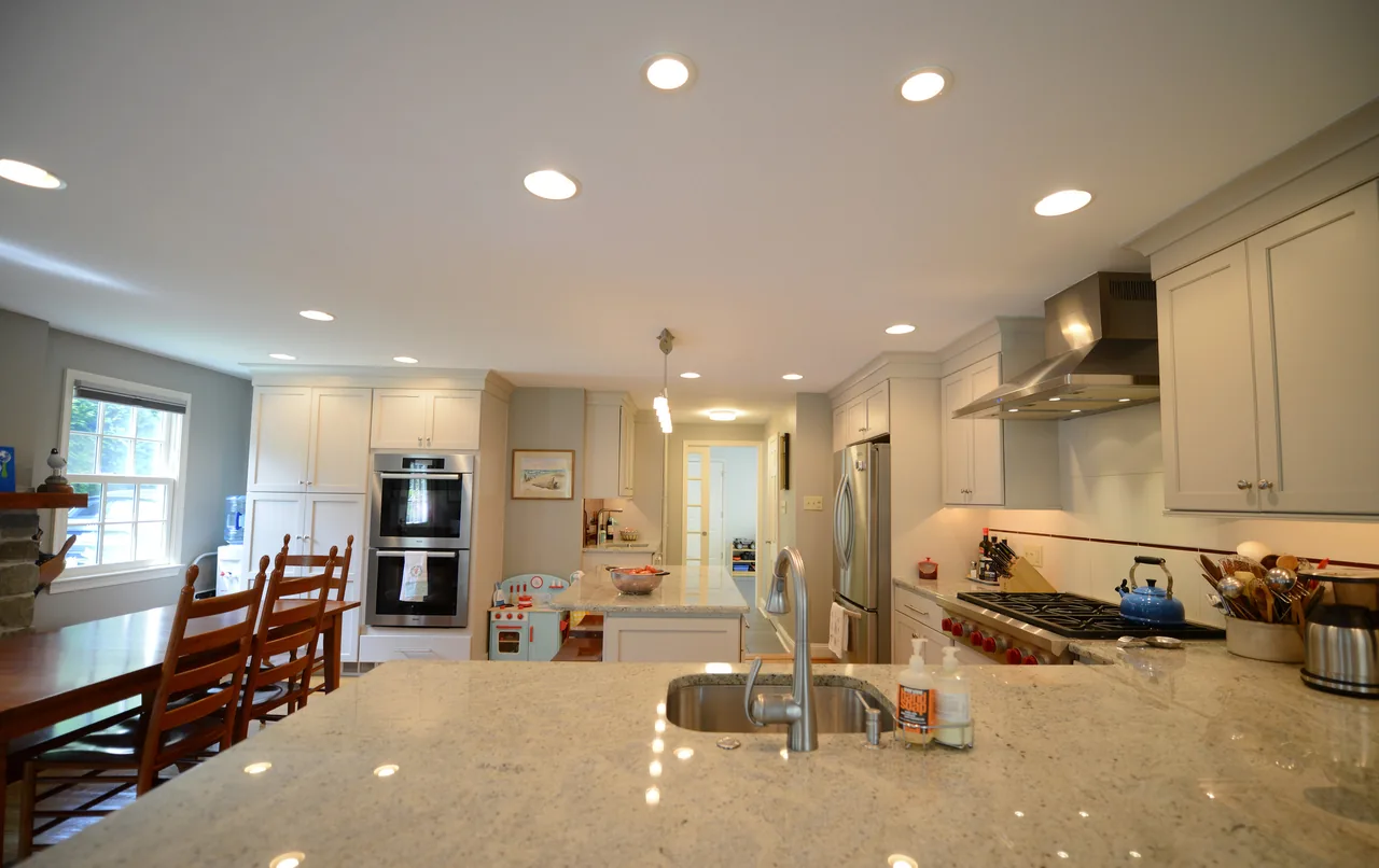 The kitchen in the Church residence features light gray cabinets, a large island with a sink, and built-in double ovens.