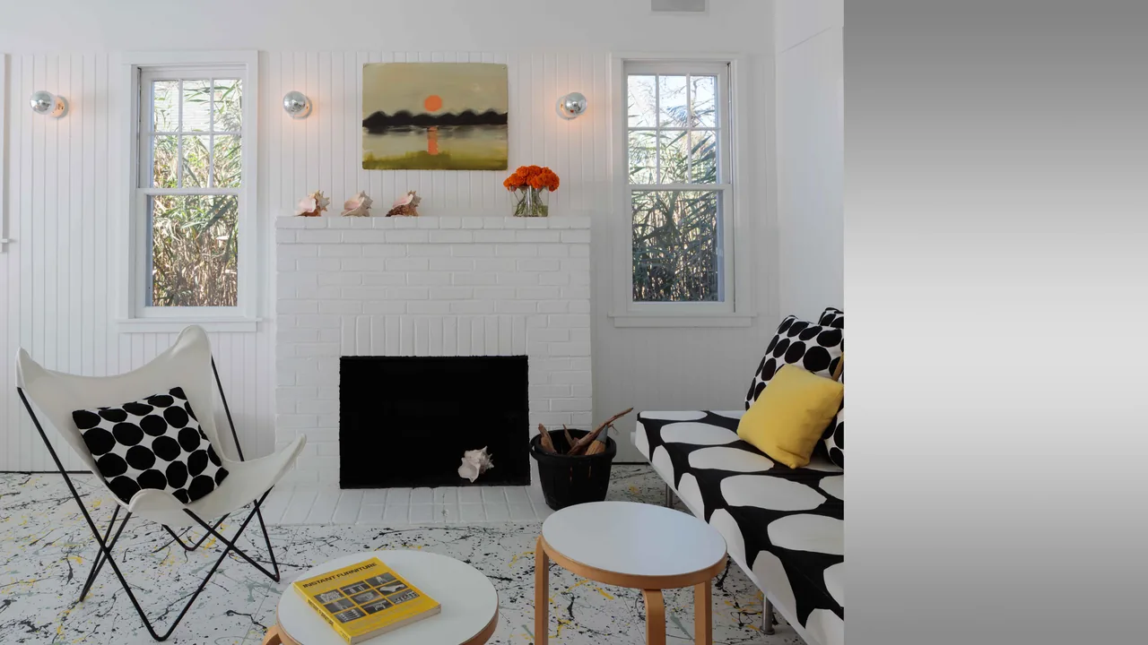 Living room in Spagnola House features a white brick fireplace and black and white patterned furniture with yellow pillows.