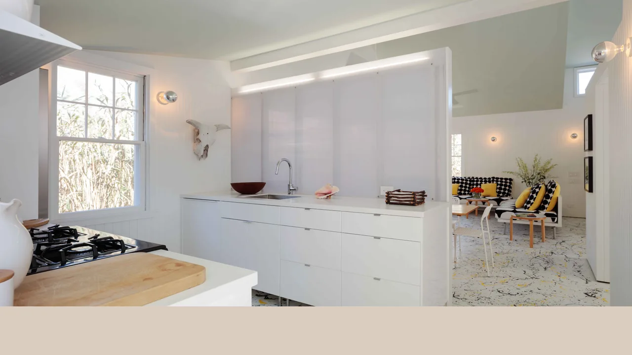 The Spagnola House features a white kitchen with gas stove and a living area with polka dot furniture and yellow accents.