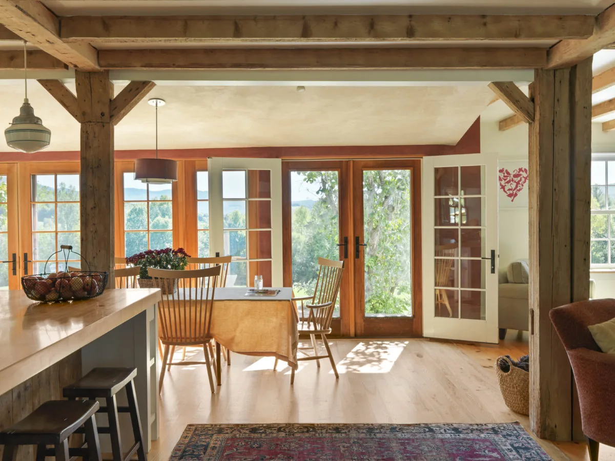 The Quaker street project features a dining space with multiple wood-framed glass doors providing ample natural light and garden views.