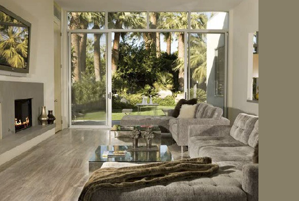 Living room in the Crescent project with sliding glass doors opening to lush garden views and a beige sectional sofa.