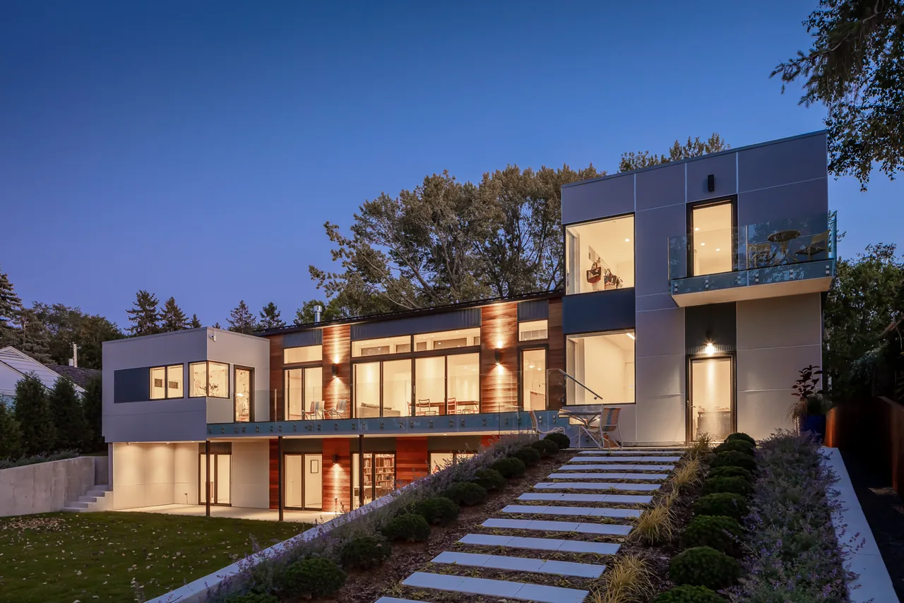 Lakefront Modern features a two-story design with glass balconies and horizontal window bands at dusk.