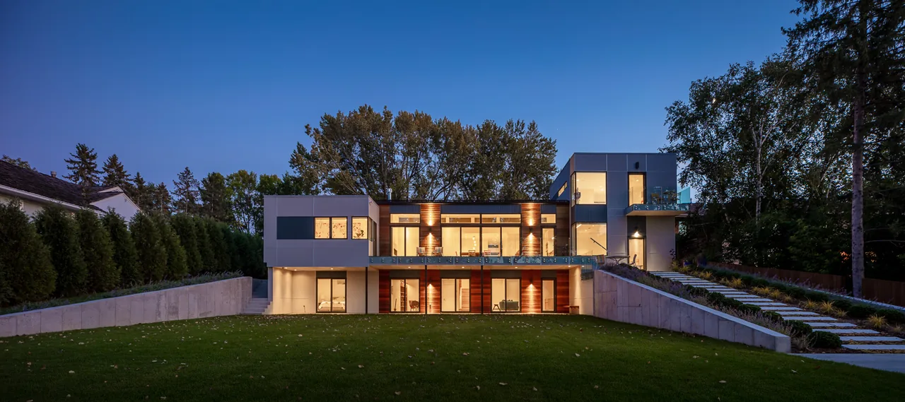 Lakefront Modern features a two-story design with glass balconies and concrete retaining walls on a sloped site.