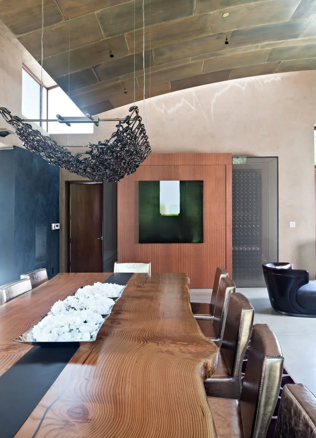 Dining room with a sculpted ceiling and a live edge wood table with built-in flowers at Saratoga Creek House.