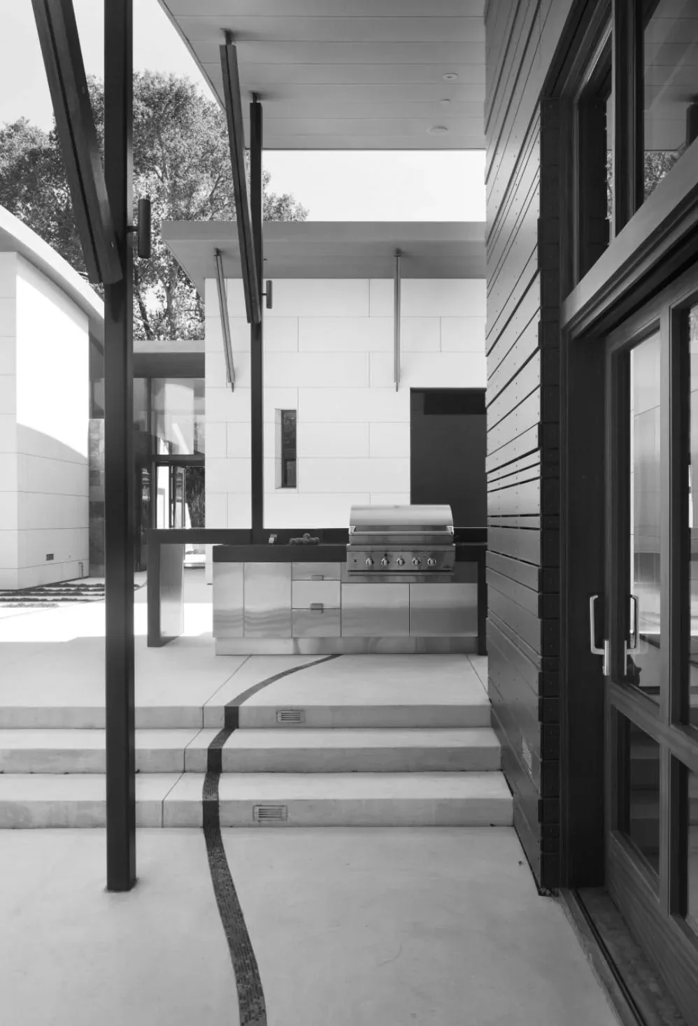 The Saratoga Creek House outdoor kitchen features stainless steel cabinetry and curved inlay concrete steps.