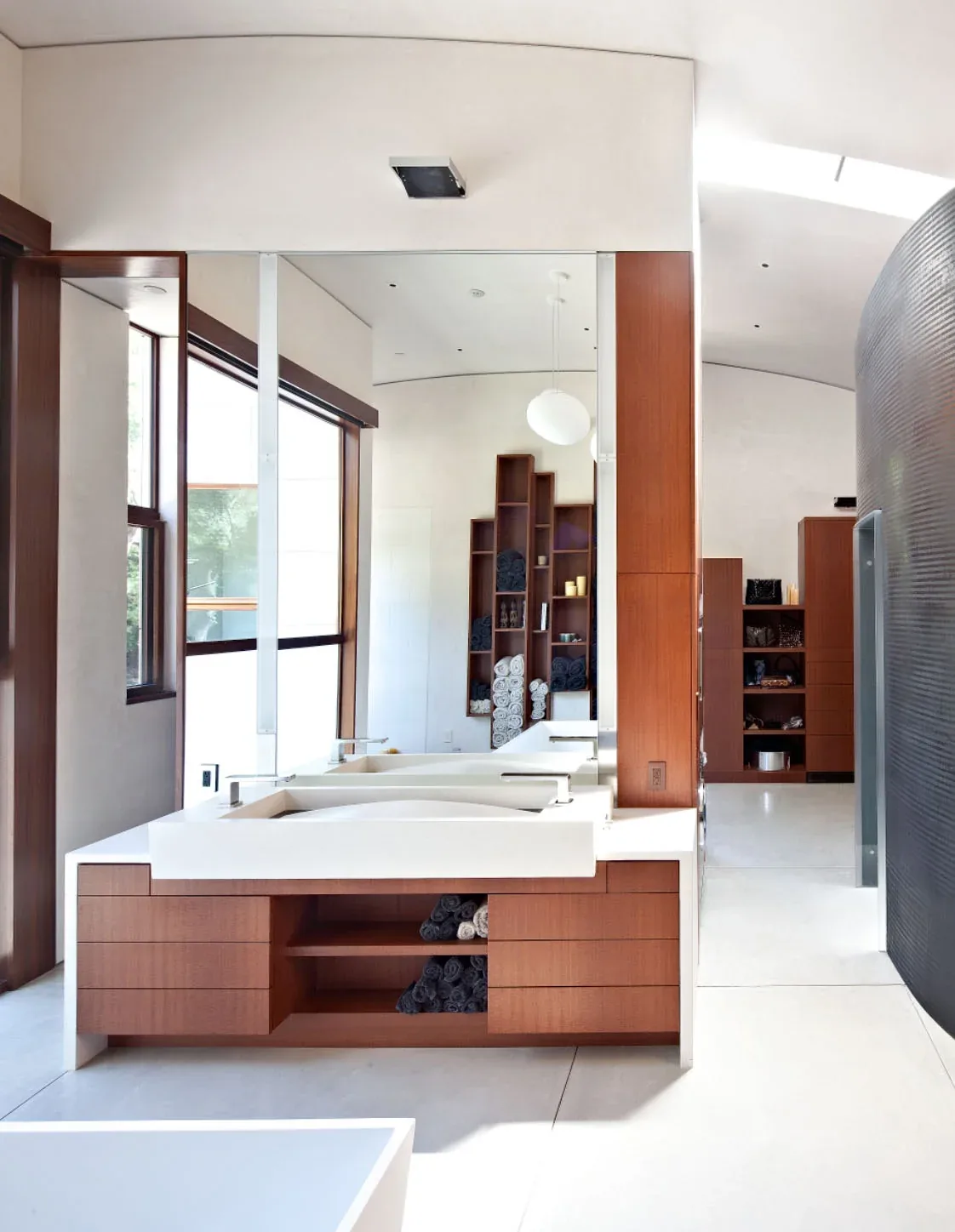 Bathroom features a rectangular sink on wood cabinetry with a large mirror and curved black wall detail.