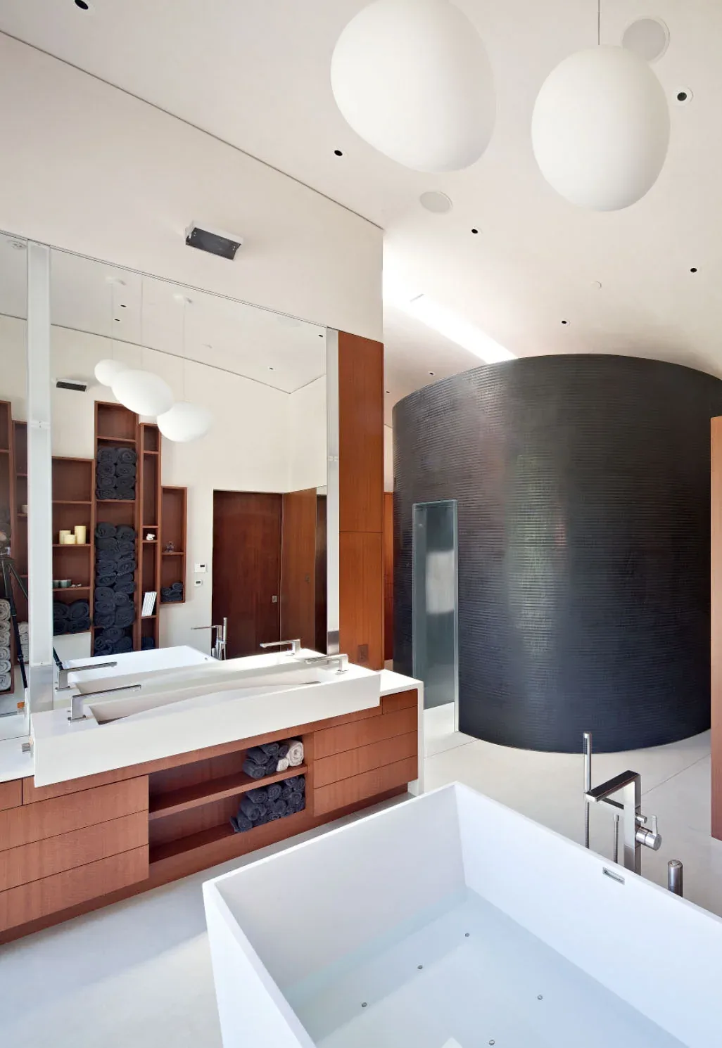 Bathroom in the Saratoga Creek House features a rectangular bathtub, double vanity with sleek faucets, and a curved black textured wall.