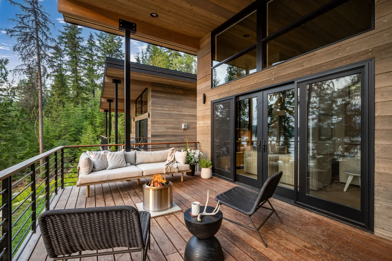 Deck area of Cedars Cabin featuring wood siding, metal railing, and outdoor seating with fire pit.