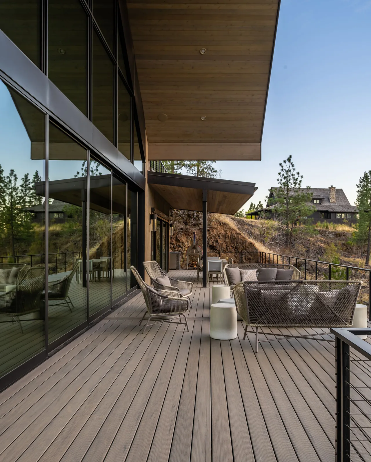 The Lakeside View project features a spacious outdoor deck with wicker seating and a dining area, connected to the interior by large sliding glass doors.