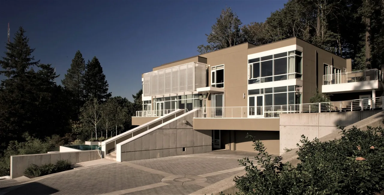 The Hewett Street Residence by TVA Architects INC. features large windows and a stepped driveway on a wooded site.