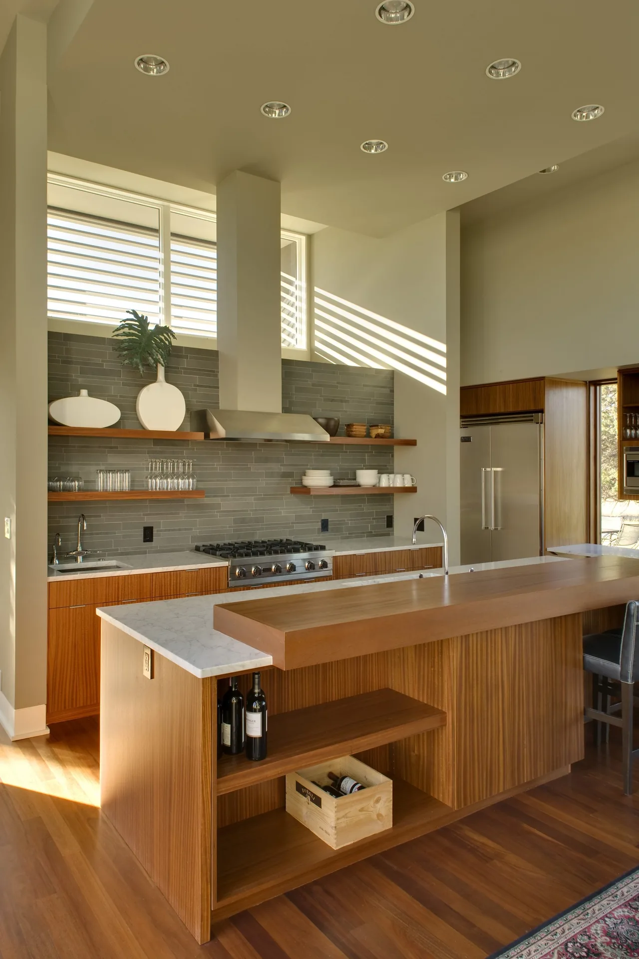 Fadjur Lane Residence kitchen by TVA Architects INC. features wood cabinetry, open shelving, and modern appliances.