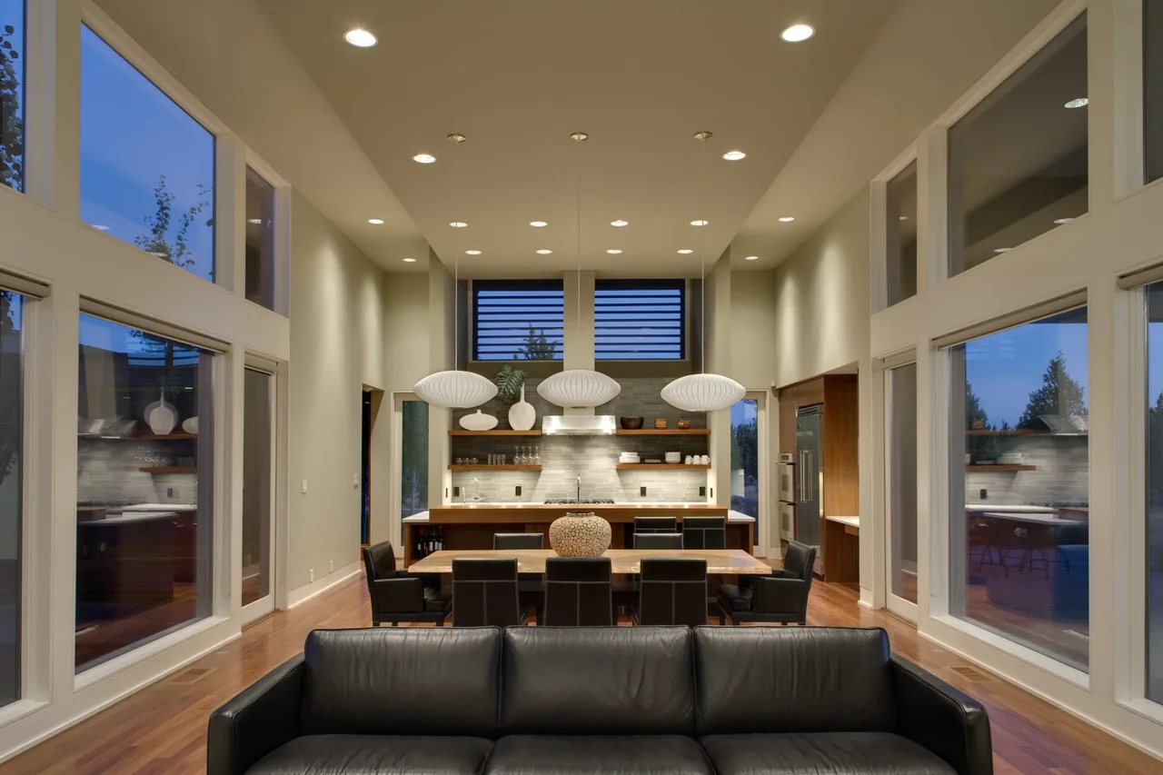The Fadjur Lane Residence features an open kitchen and dining space with floor-to-ceiling windows and pendant lighting.