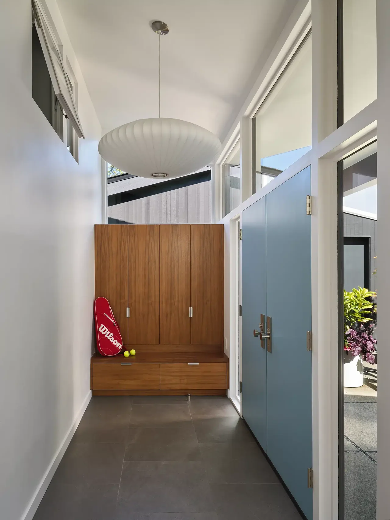 Entry hallway in Magnolia Mid-Century Modern project with built-in wood storage and large pendant light.