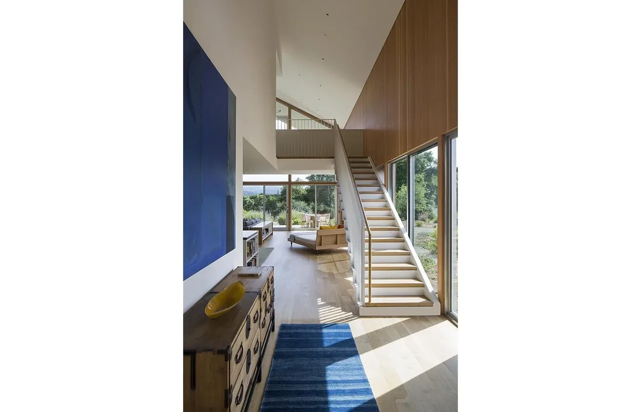 South Bay Residence features a wood-paneled wall, floating stairs, and garden-view windows.