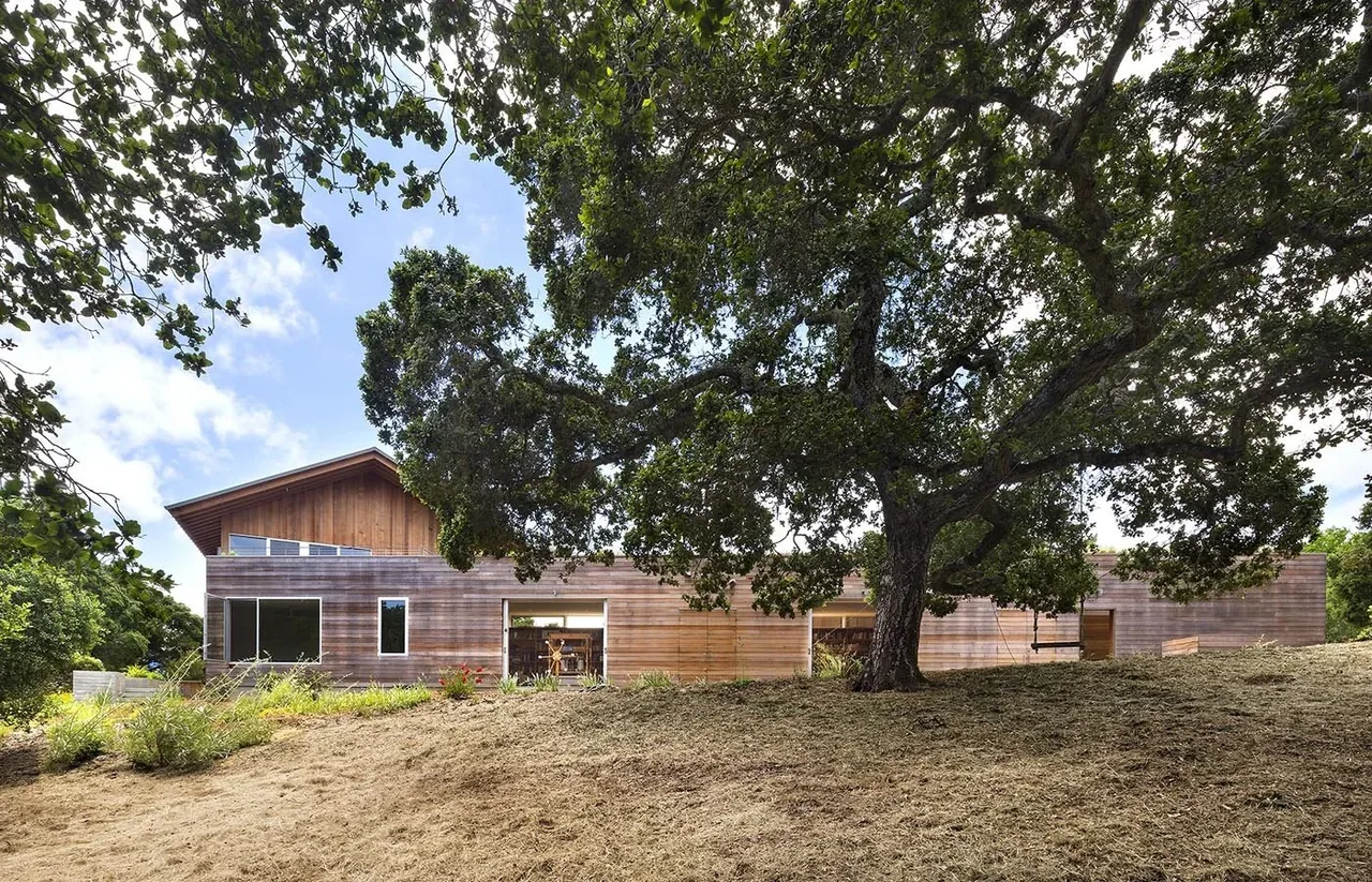 South Bay Residence features horizontal wood siding and large window openings under a gable roof.
