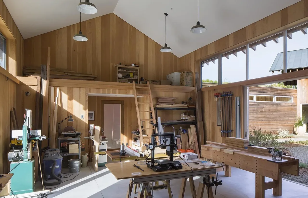Woodworking workshop interior with natural wood paneling and large windows providing abundant daylight.