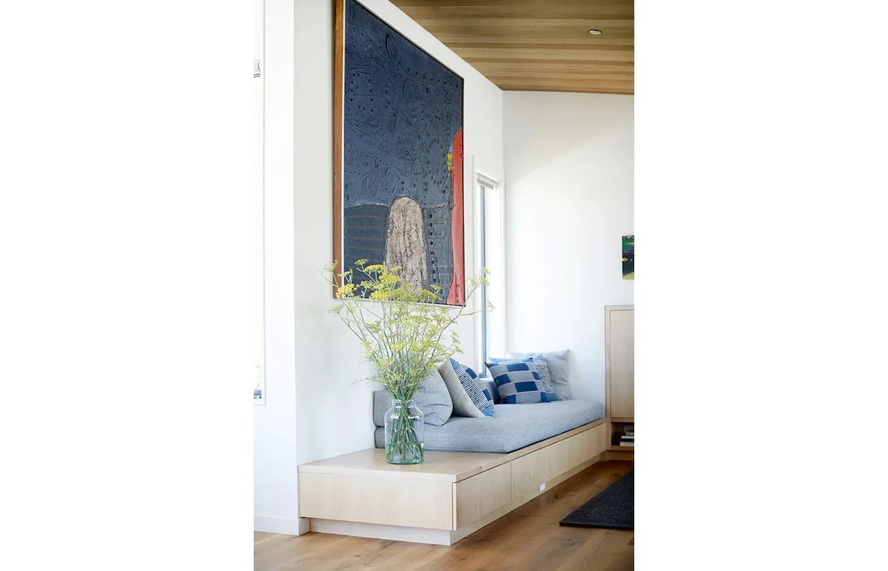 Nook features built-in bench with cushions, under an exposed wood ceiling with angled panels.
