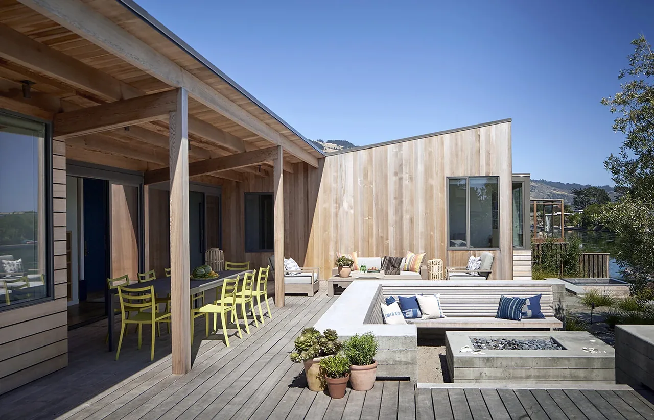 The Stinson Beach Lagoon project features a wooden outdoor living terrace with a covered dining area and sunken concrete seating around a fire pit.