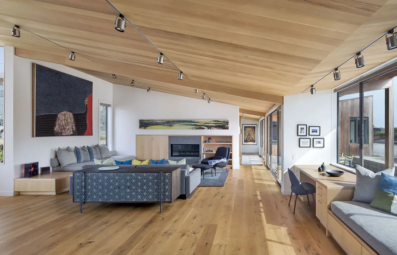 Living room with exposed wood ceiling and large sliding glass doors opening to outdoor space at Stinson Beach Lagoon.