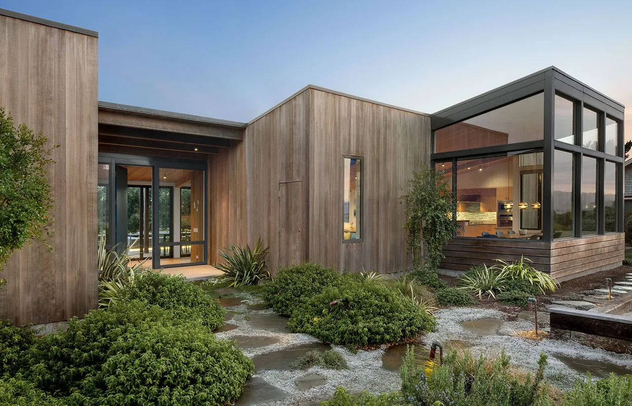Stinson Beach Lagoon by Turnbull Griffin Haesloop features wood siding and expansive black-framed windows with a view into the dining area.