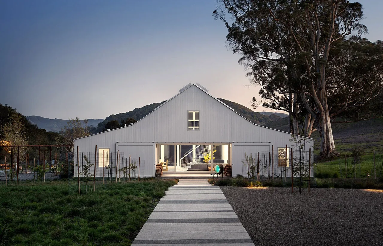 Hupomone Ranch features a modern barn-style house with large open entryway and minimalistic landscape.