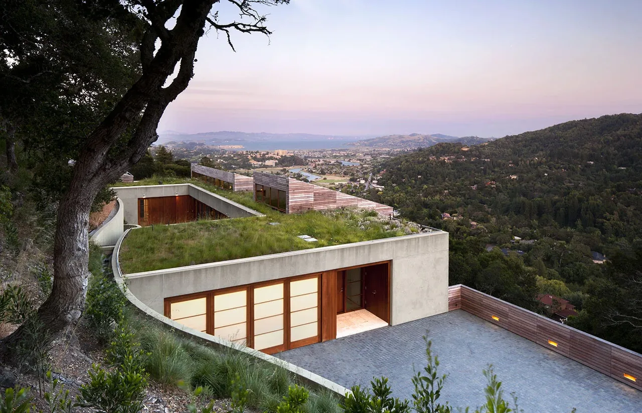 Kentfield Residence features a green roof and wood-framed glass doors with extensive valley views at sunset.