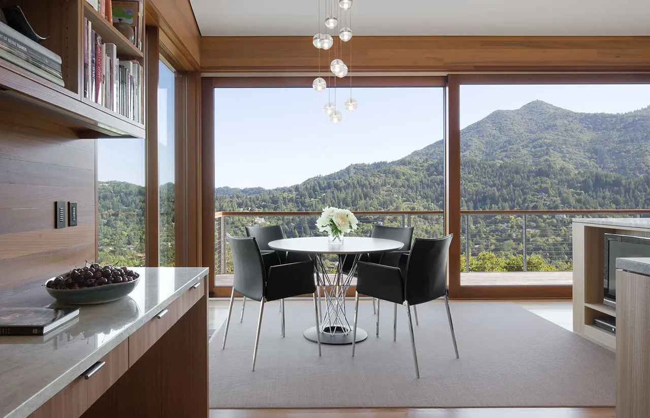 Kentfield Residence dining area with wood-framed glass doors opening to balcony and mountain views.