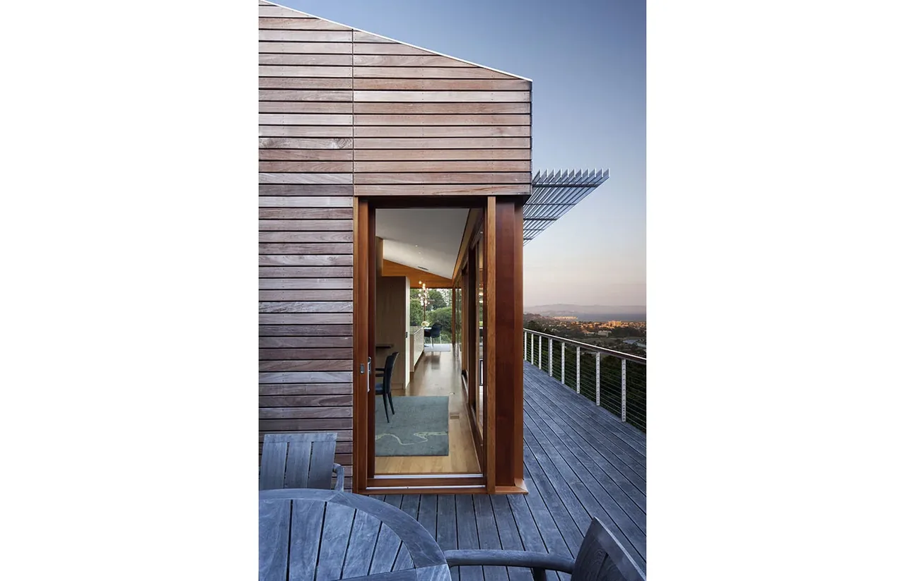 Kentfield Residence by Turnbull Griffin Haesloop features a wood paneled exterior with a deck and large wood framed glass door.