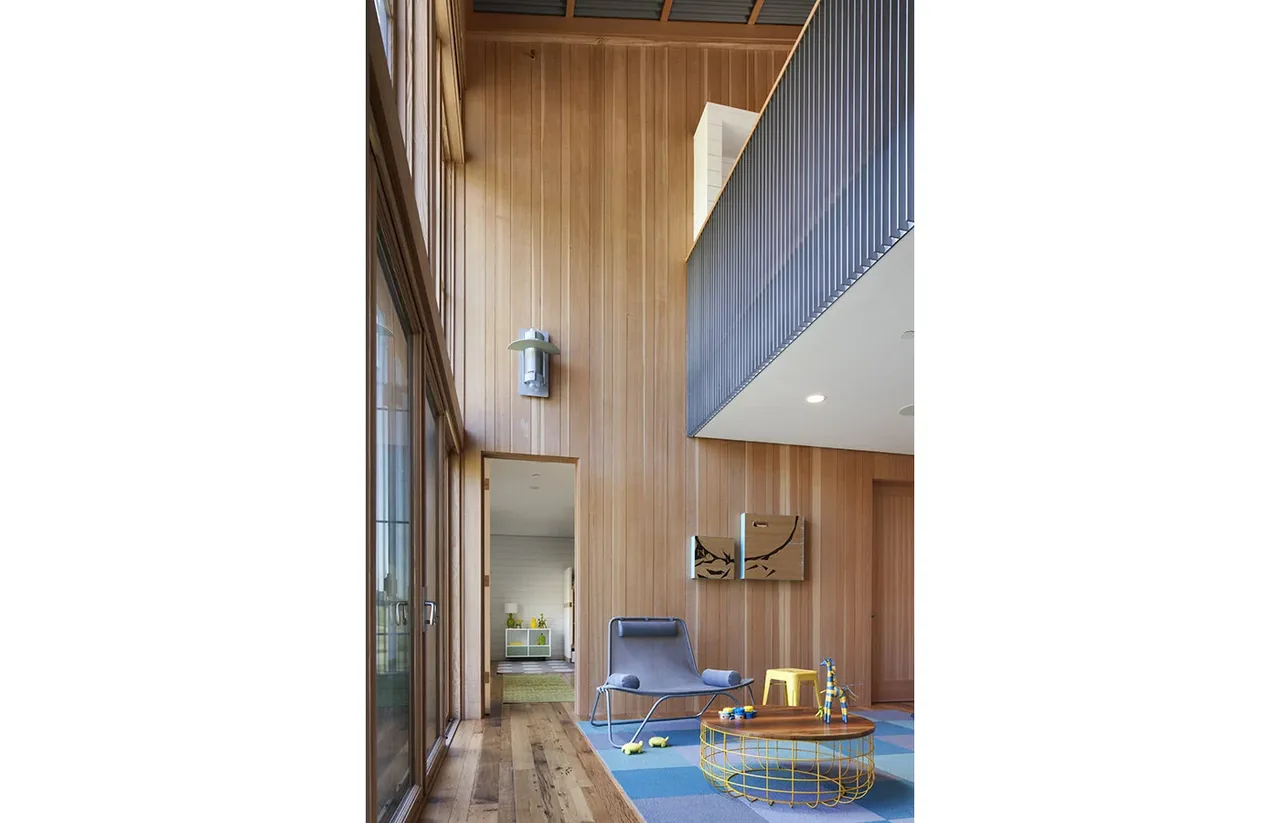 Open living area featuring wood-paneled walls and a metal railing balcony above.