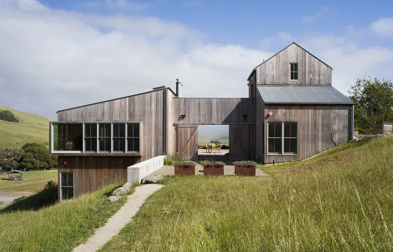 West Marin Ranch features a wood-clad contemporary ranch house with a breezeway connecting two structures on a hillside.