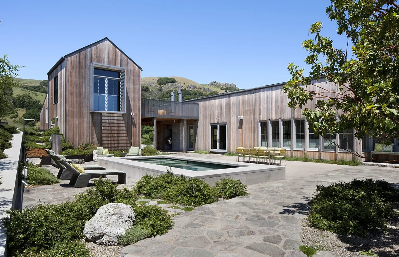 West Marin Ranch features a wooden exterior with a courtyard pool and outdoor seating in a hillside landscape.