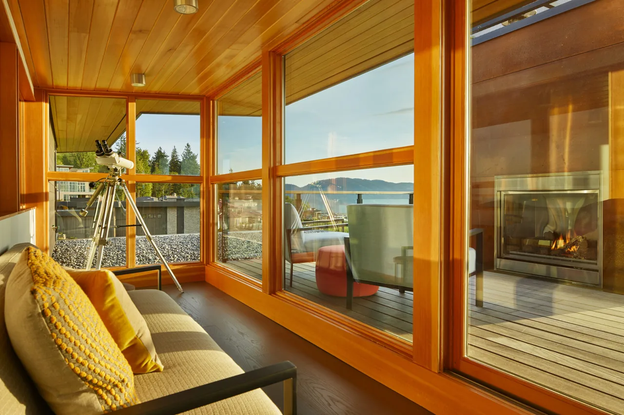 Seating nook with telescope and large windows facing an outdoor patio with fireplace and mountain views at Issaquah Highlands Residence