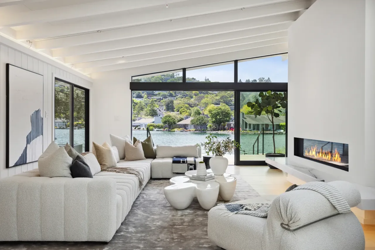 Living room with floor-to-ceiling glazing and a recessed linear fireplace facing a waterfront view.
