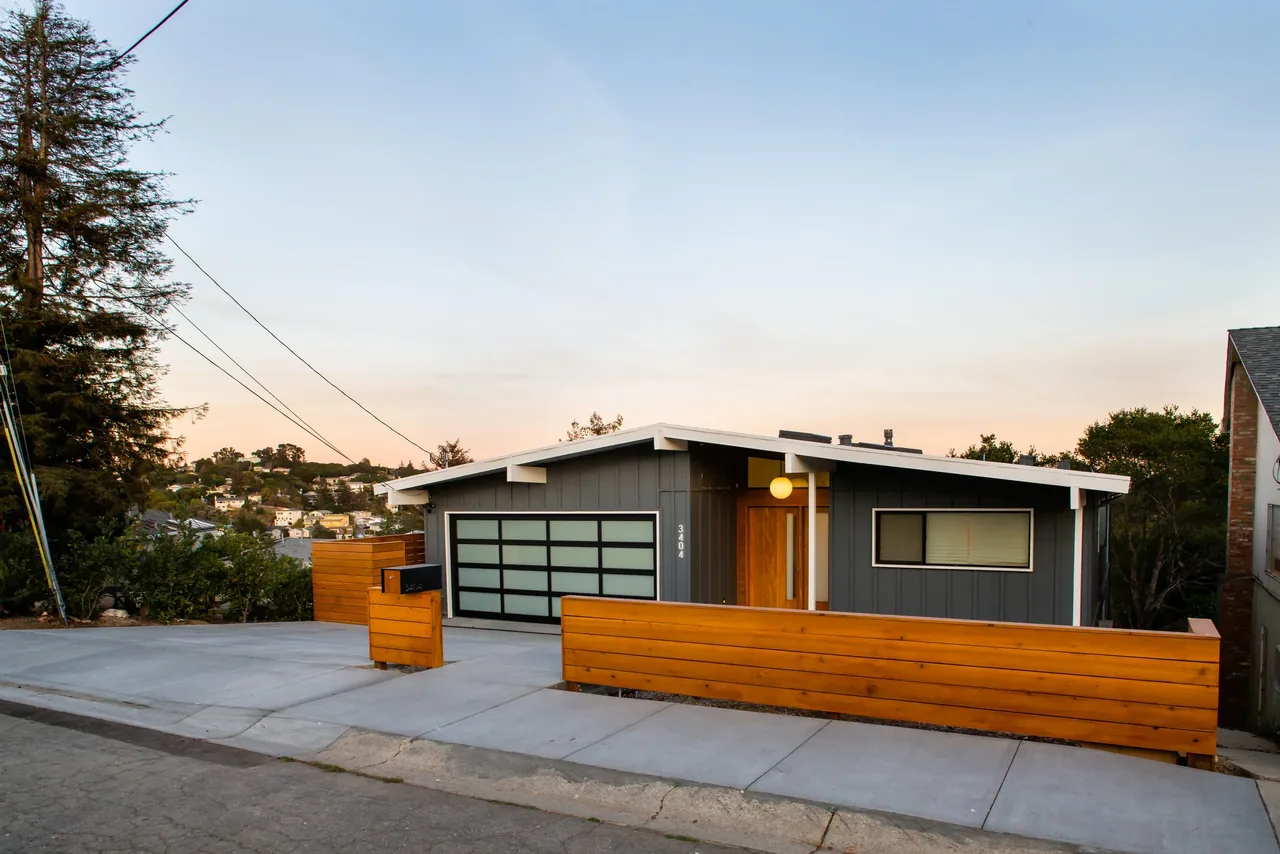Belmont Country Club home by GTL Architecture & Interiors features horizontal wood siding and a glass garage door.