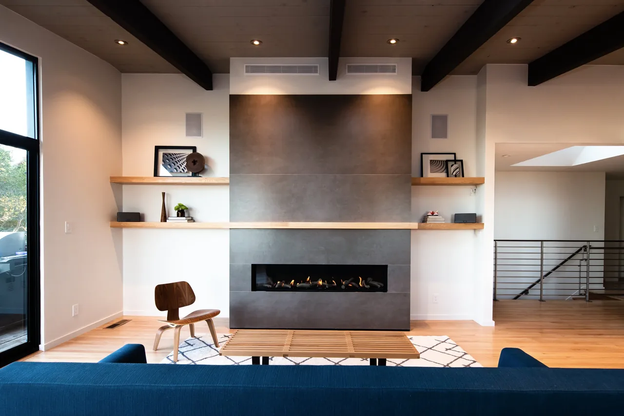 Living room features a dark gray fireplace wall framed by natural wood shelves and ceiling beams.