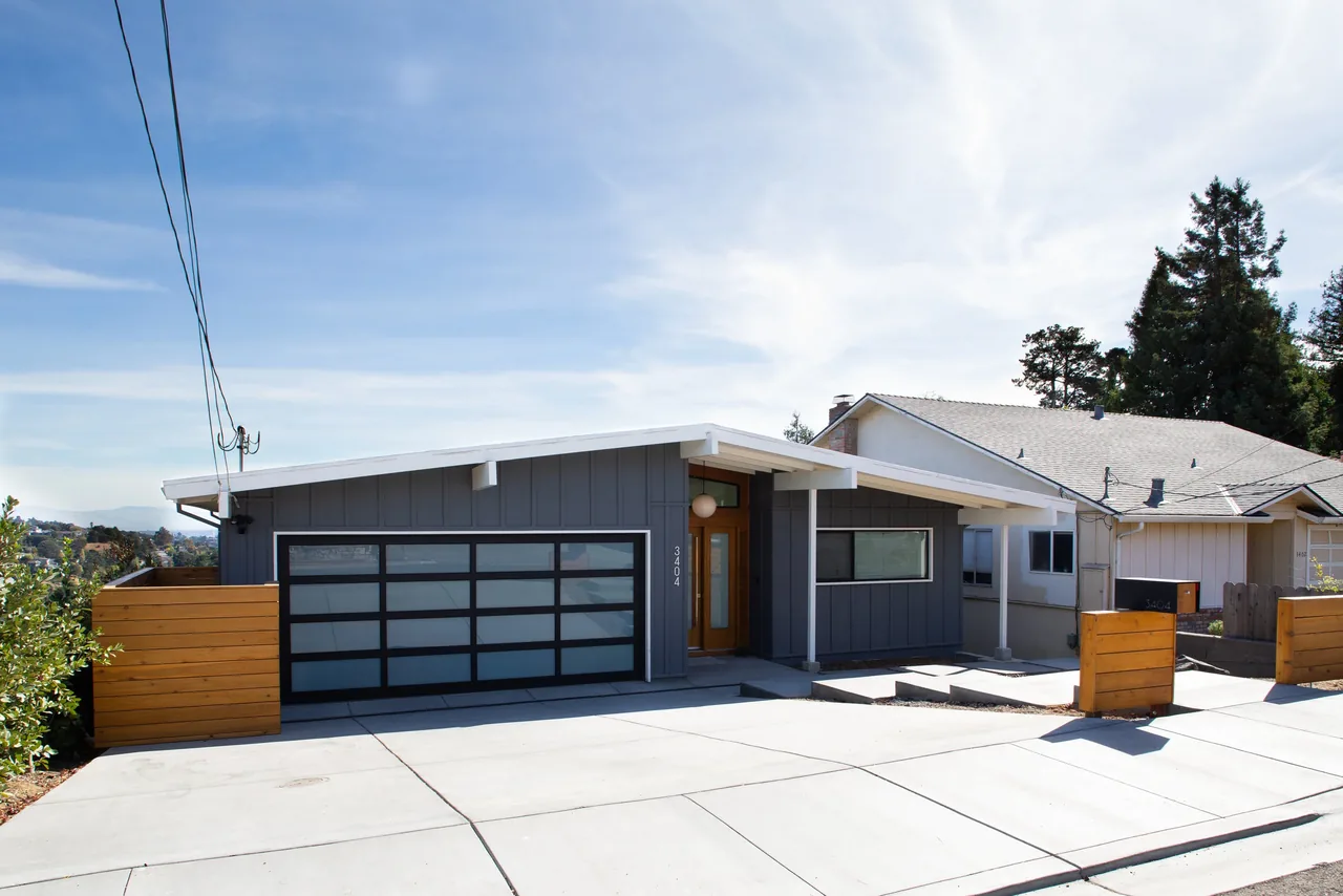 The Belmont Country Club project features a modern single-story home with flat roof and glass-paneled garage door.