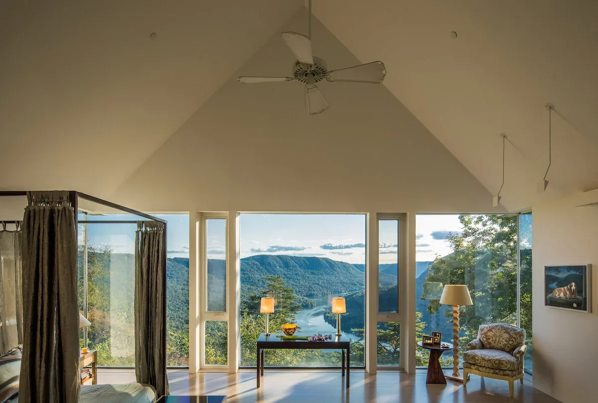 The Mills Residence living room features a vaulted ceiling and expansive windows framing a river view.