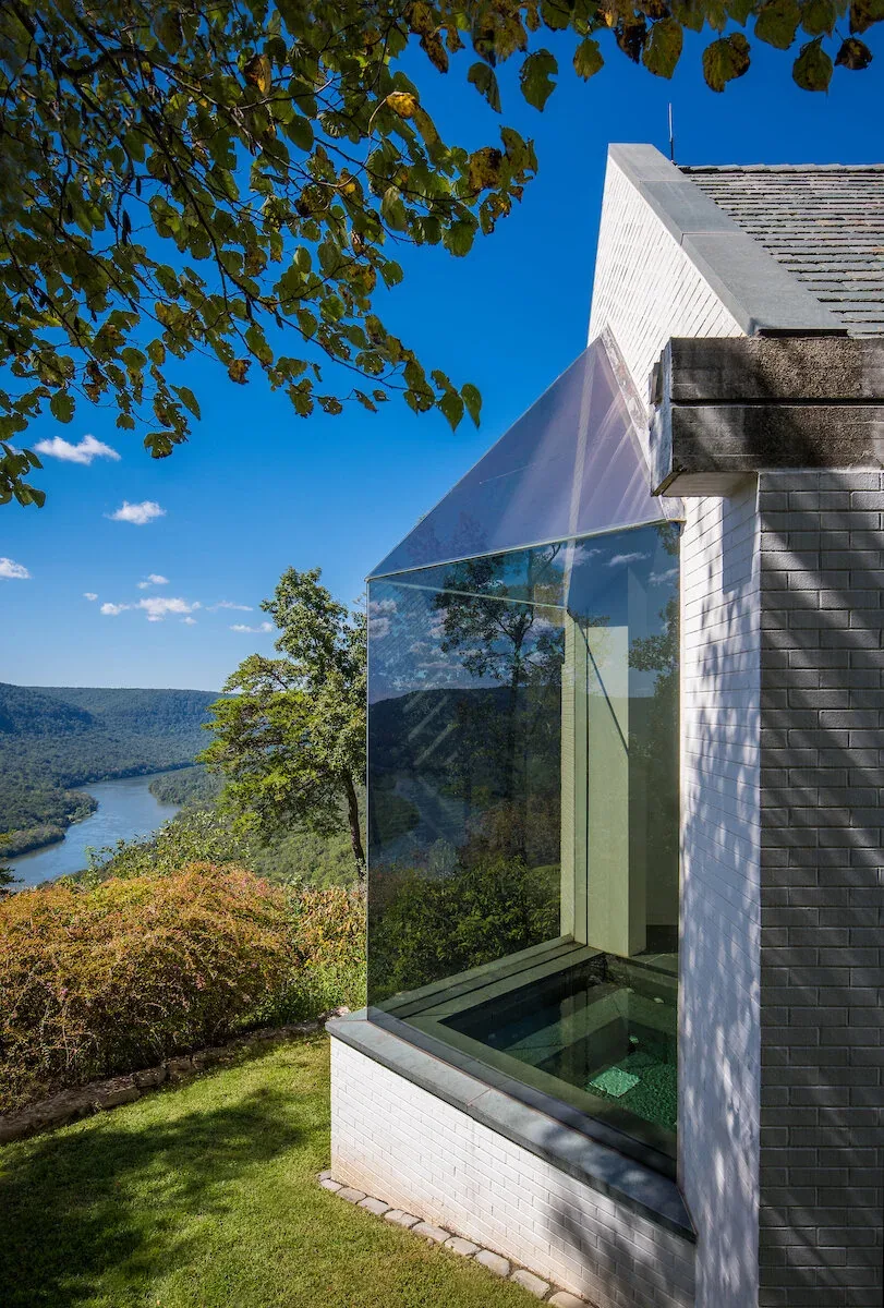 The Mills Residence exterior corner with a large glass bay window offering scenic river views.