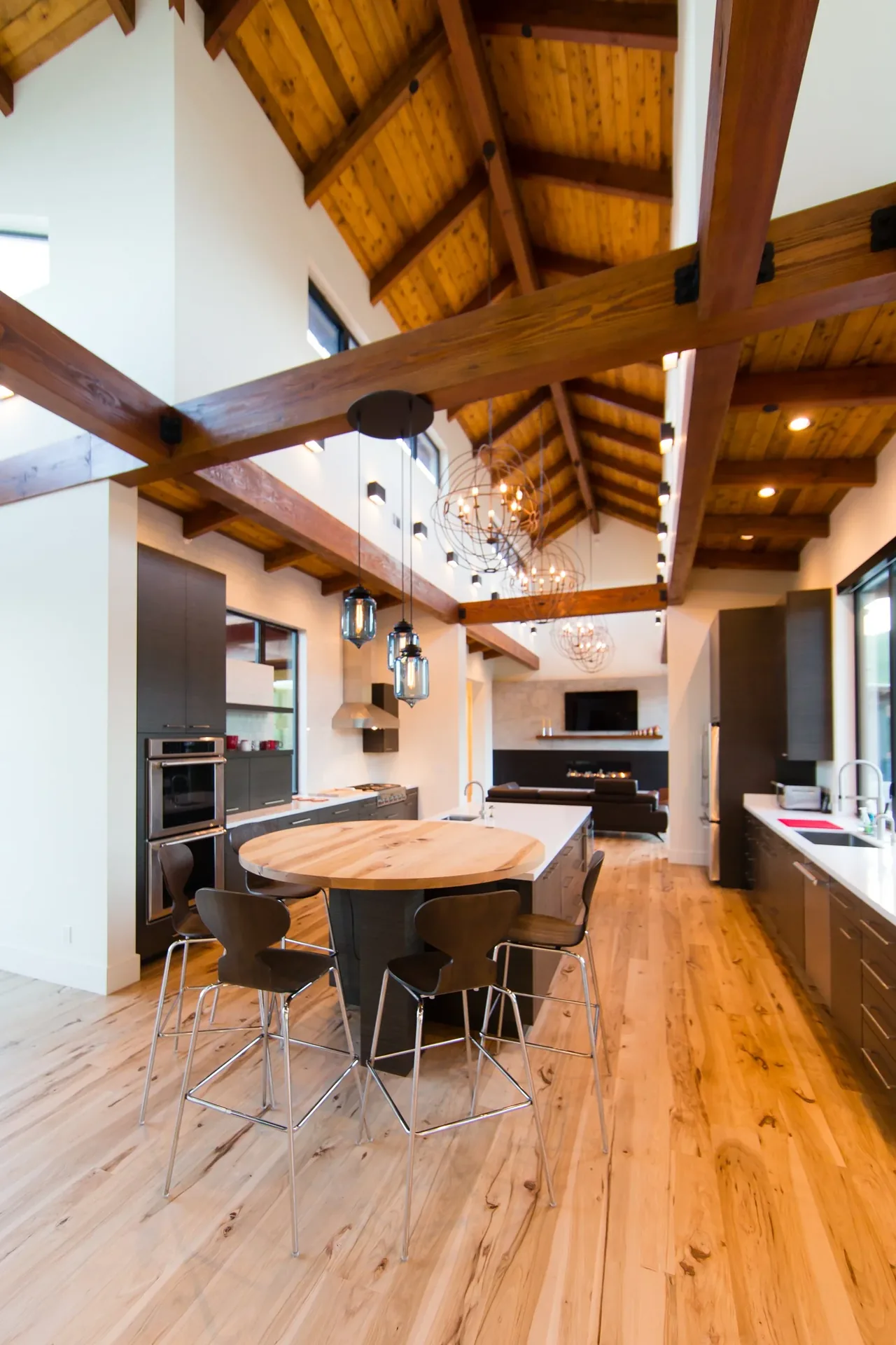 Cayucos Ranch kitchen and living area feature vaulted wood ceilings and mixed wood flooring with modern dark cabinetry.