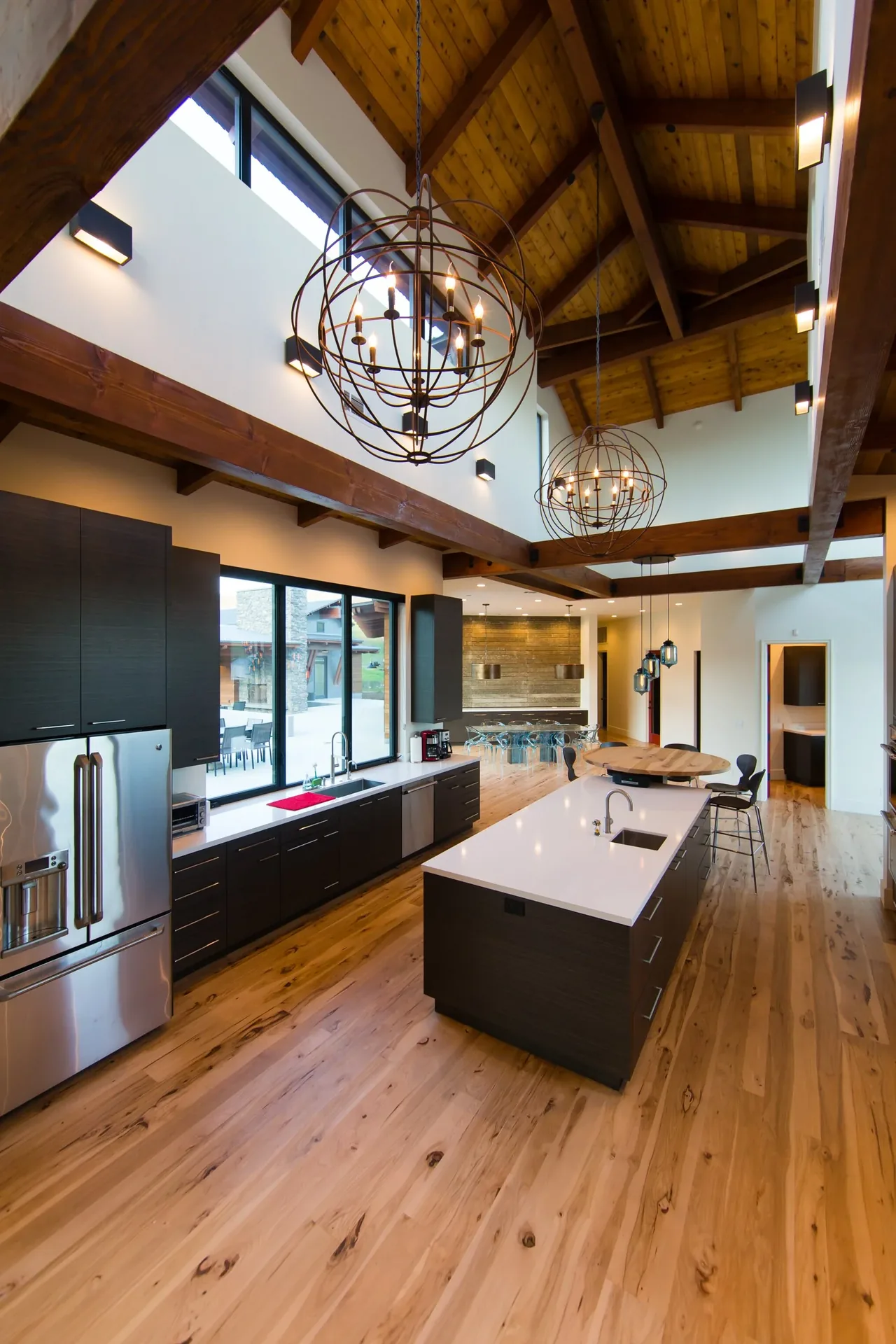 Kitchen area with vaulted wood ceiling and large island featuring a sink and seating.