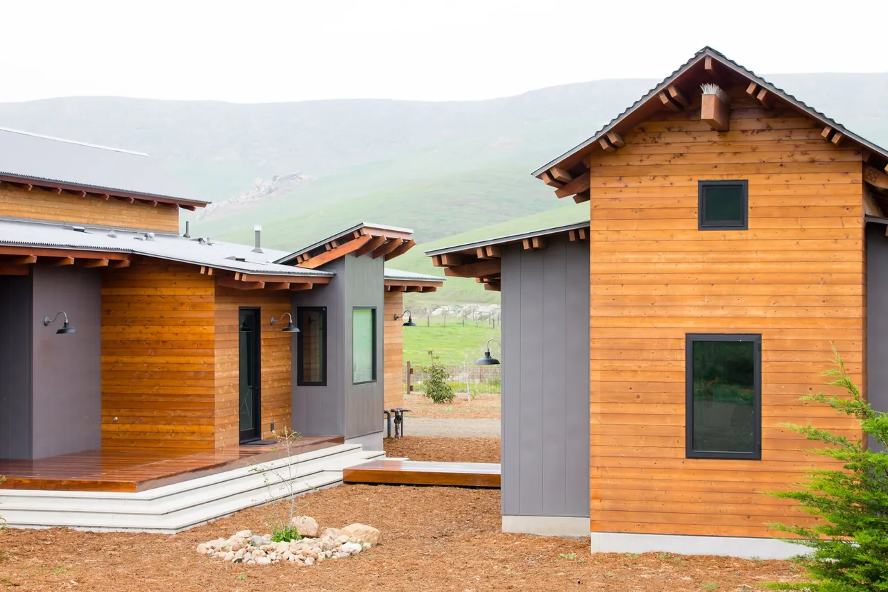 Two modern residential buildings with wood siding and gray metal panels at Cayucos Ranch by Crabtree Architecture + Design.