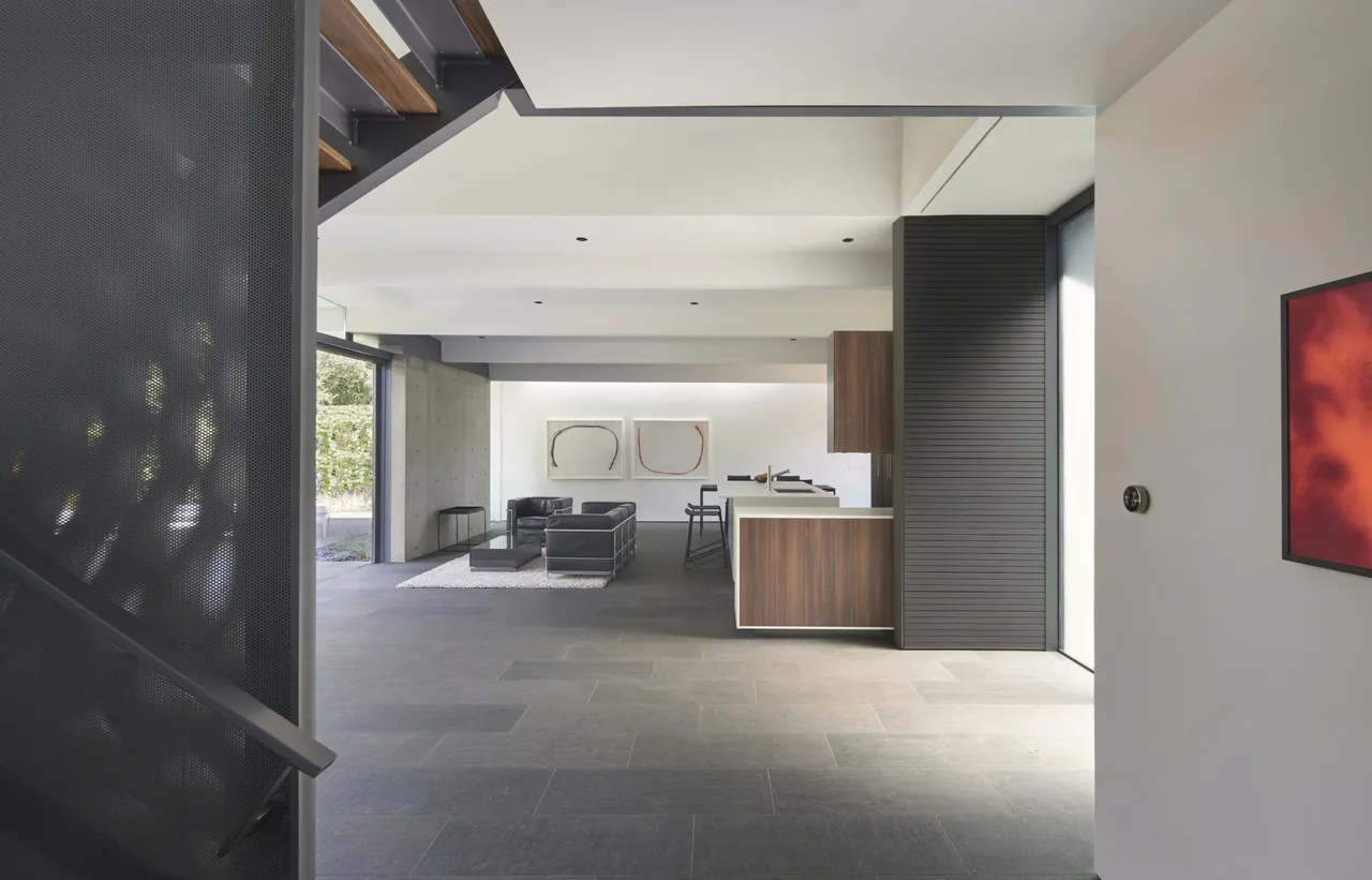 Open living and kitchen space with large stone tile flooring in Edgewood House by Terry & Terry Architecture.