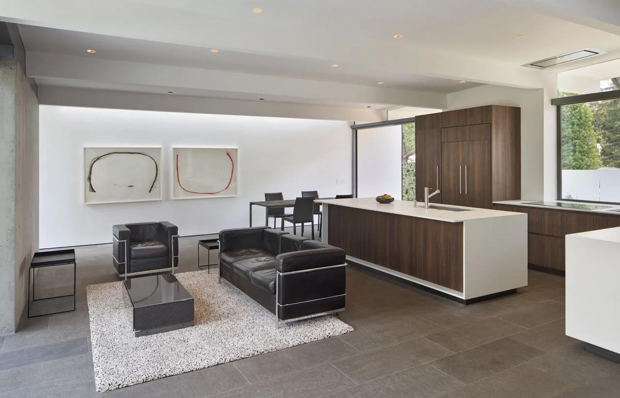 Edgewood House features an open living and kitchen area with black leather seating and a dark wood kitchen island.