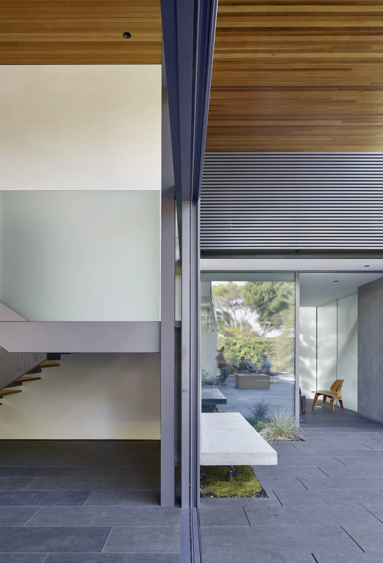 Edgewood House features a wood soffit ceiling, stone tile floor, and a seamless transition between indoor and outdoor spaces.
